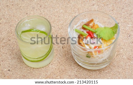 fried Egg Salad pepper with rice noodle and lemon drink on wood table