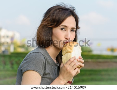 portrait girl happy and eat bread for picnic resting at garden