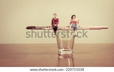 Miniature people sitting on paint brush concept painting tool with retro filter