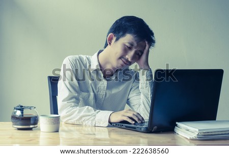 asian depressed business man working and laptop with retro filter