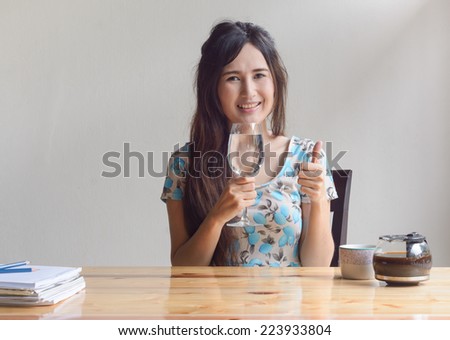 asian woman drink water and show thumb up at work table