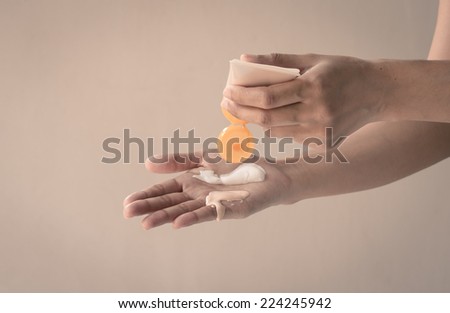 woman hands with skin care cream at wall background with retro filter