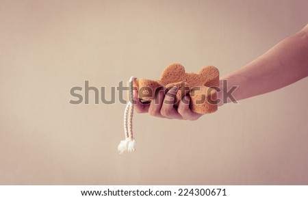 sponge bath in a woman hand on a wall background with retro filter