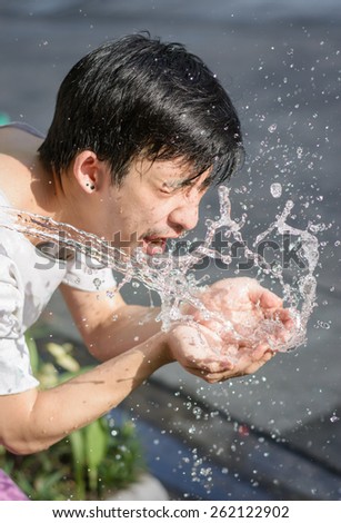 asia young man washing him face with Water splash. at outdoor