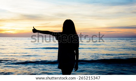 silhouette happy woman thumb up on the sunset at the beach