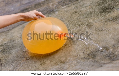 hand play yellow water balloon at outdoor on floor