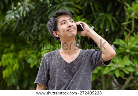 happy asia man using and talk smart phone at outdoor natural