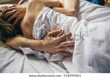 beautiful couple lying together on the bed. male hand closeup