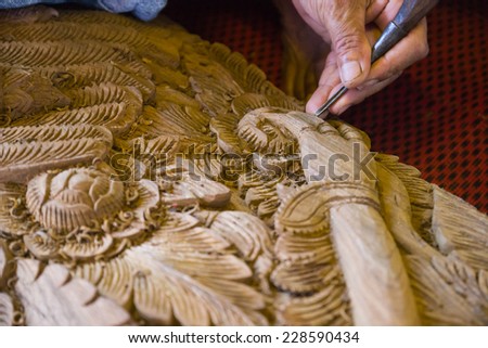 CHIANGMAI, SEPTEMBER 21: the view of the craftsman\'s hand using the chisel to engrave thailand traditional design on splat for decoration on September 21, 2014 in Chiangmai, Thailand