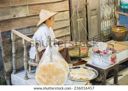 Loei, Thailand - October 26, 2014: asian woman sells thailand traditional snack crispy rice on charcoal stove at Chiangkarn night market in Loei province.