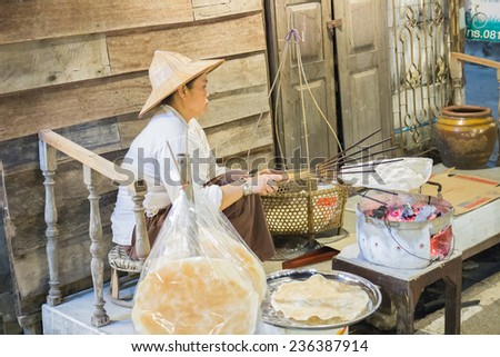 Loei, Thailand - October 26, 2014: The asian seller grills thailand traditional snack crispy rice on charcoal stove at Chiangkarn night market in Loei province.