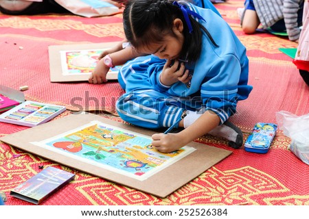 Chiangmai, Thailand - December 18, 2014: The asian girl is painting crayon color on her drawing for drawing contest at royal project fair on December 18, 2014 in Chiangmai, Thailand.