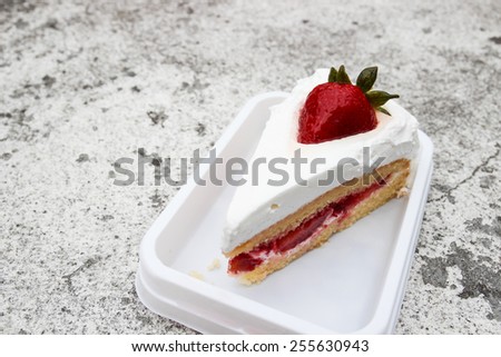 strawberry cheese cake with cream on top on cement floor