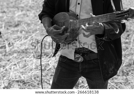 Thailand traditional musician hillbilly playing country folk music in rice paddy field, black and white