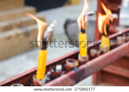 blurry defocused image of flame of candle for worship in thailand temple for background