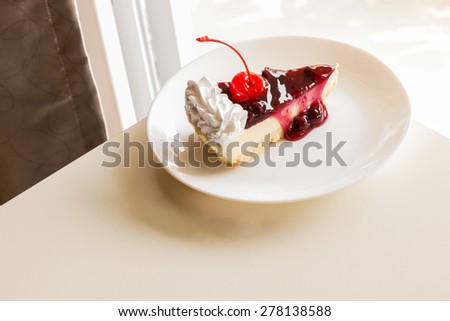 piece of blueberry cheese cake with cherry on top