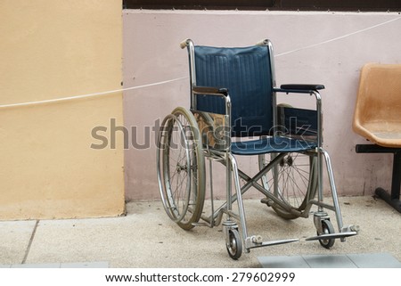 old wheelchair beside the beige wall of the building