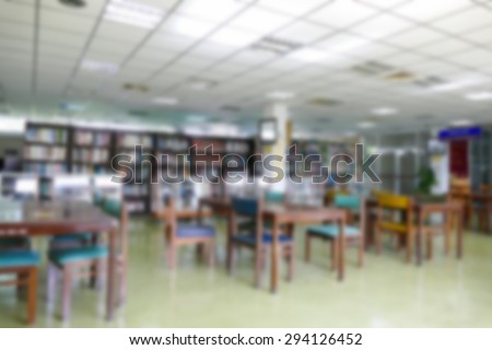 blurry defocused image of book shelf, wooden desk and chair for reading book in the university library