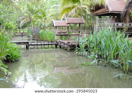 wooden bridge across the pond and thailand traditional house in the garden