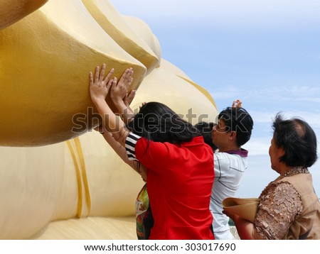 Ang Thong, Thailand - August 1, 2015: buddhist people touch the finger of big golden buddha statue in Muang temple.