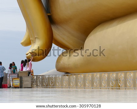 Ang Thong, Thailand - August 1, 2015: buddhist people touch the finger of big golden buddha statue in Muang temple.