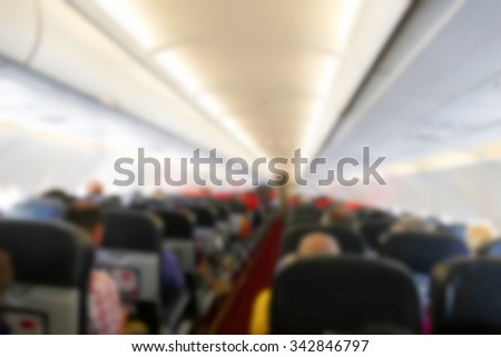 blurry defocused image of people sitting in economy class seat in the airplane