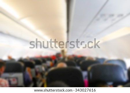 blurry defocused image of people sitting in economy class seat in the airplane