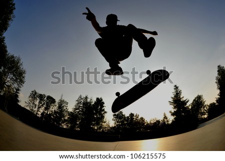 perfect silhouette of a skateboarder doing a flip trick at the skate park.
