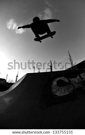 perfect silhouette of a skateboarder jumping high at the skate park.