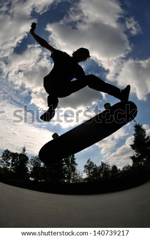 perfect silhouette of a skateboarder jumping high at the skate park.