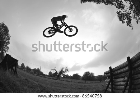 Silhouette of a young man performing a radical mountain bike jump