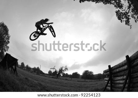 Silhouette of a young man performing a radical mountain bike jump