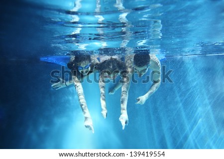 Three children smiling and having fun underwater