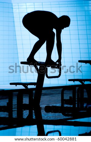 Silhouette of swimmer on starting platform on swimming pool
