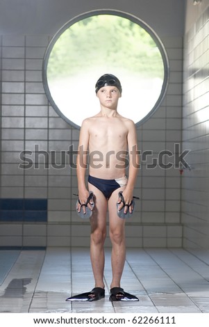 Boy standing on swimming pool with cap,googles and fins