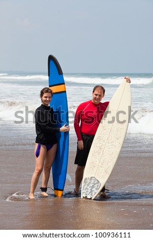 young man and the girl with boards for surf on an ocean coast