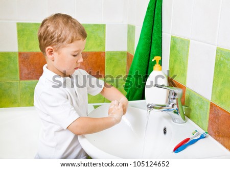 little boy in a bathroom washes with hand soap.