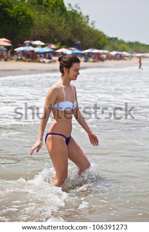 attractive girl in bikini enters into water to bathe at the ocean