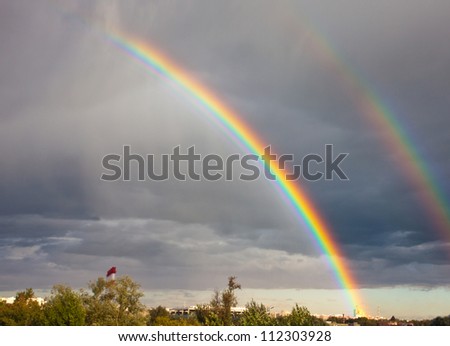 Double rainbow under city  in the cloudy sky