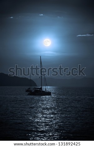 Sailing yacht illuminated by the light of a full moon