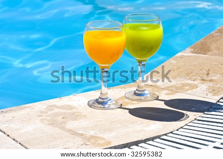Two glasses with juice on the brink of pool