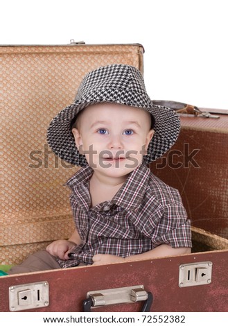 The small smiling boy sits in an open road suitcase. Isolated on a white background