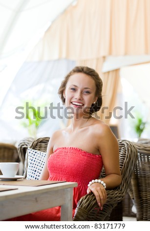 Young girl in a pink dress seated at a table in the summer restaurant