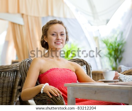 Young girl in a pink dress seated at a table in the summer restaurant