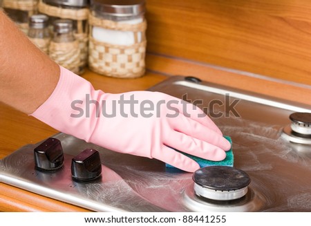 hand of the person in a rubber glove cleans a kitchen gas cooker