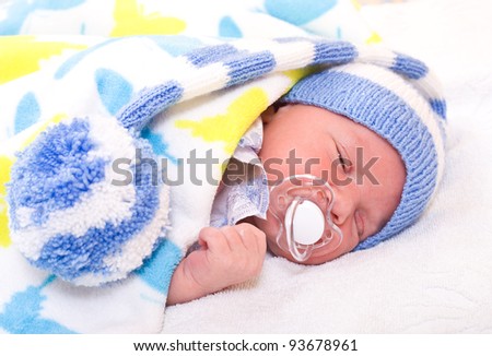 newborn baby (at the age of 7 days) sleeps in a knitted striped hat