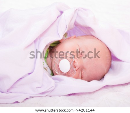 newborn baby (at the age of 7 days) in a knitted striped hat