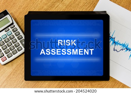 risk assessment word on digital tablet with calculator and financial graph