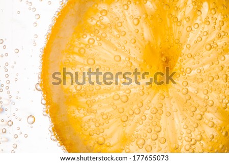 close-up of lemon slice in clear water with bubbles