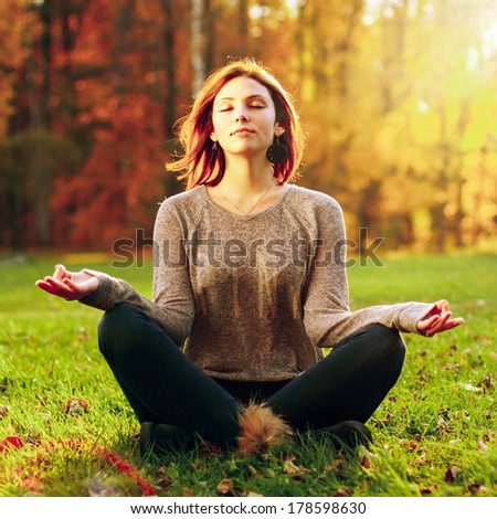 Beautiful young girl meditating in autumn park